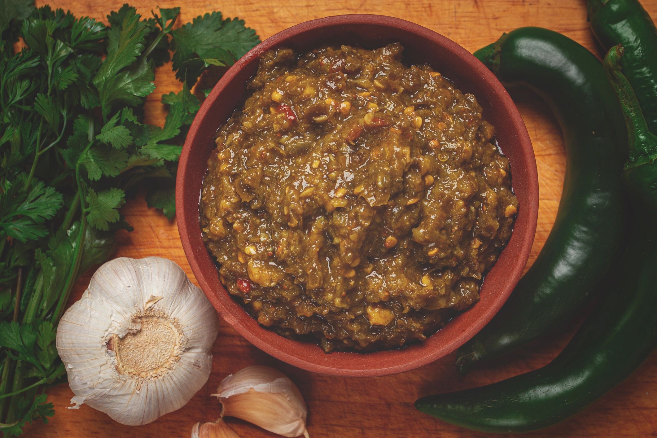 Green sauce in a clay bowl on a wooden board